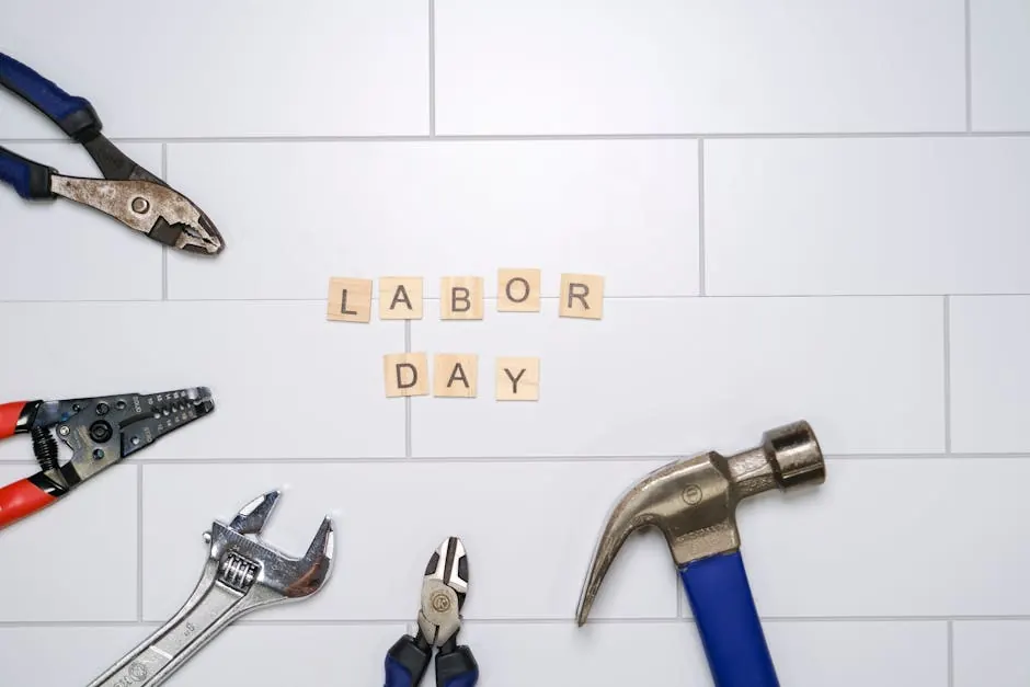 Flat lay of various tools and 'Labor Day' letters on white tiles. Perfect for Labor Day themes.